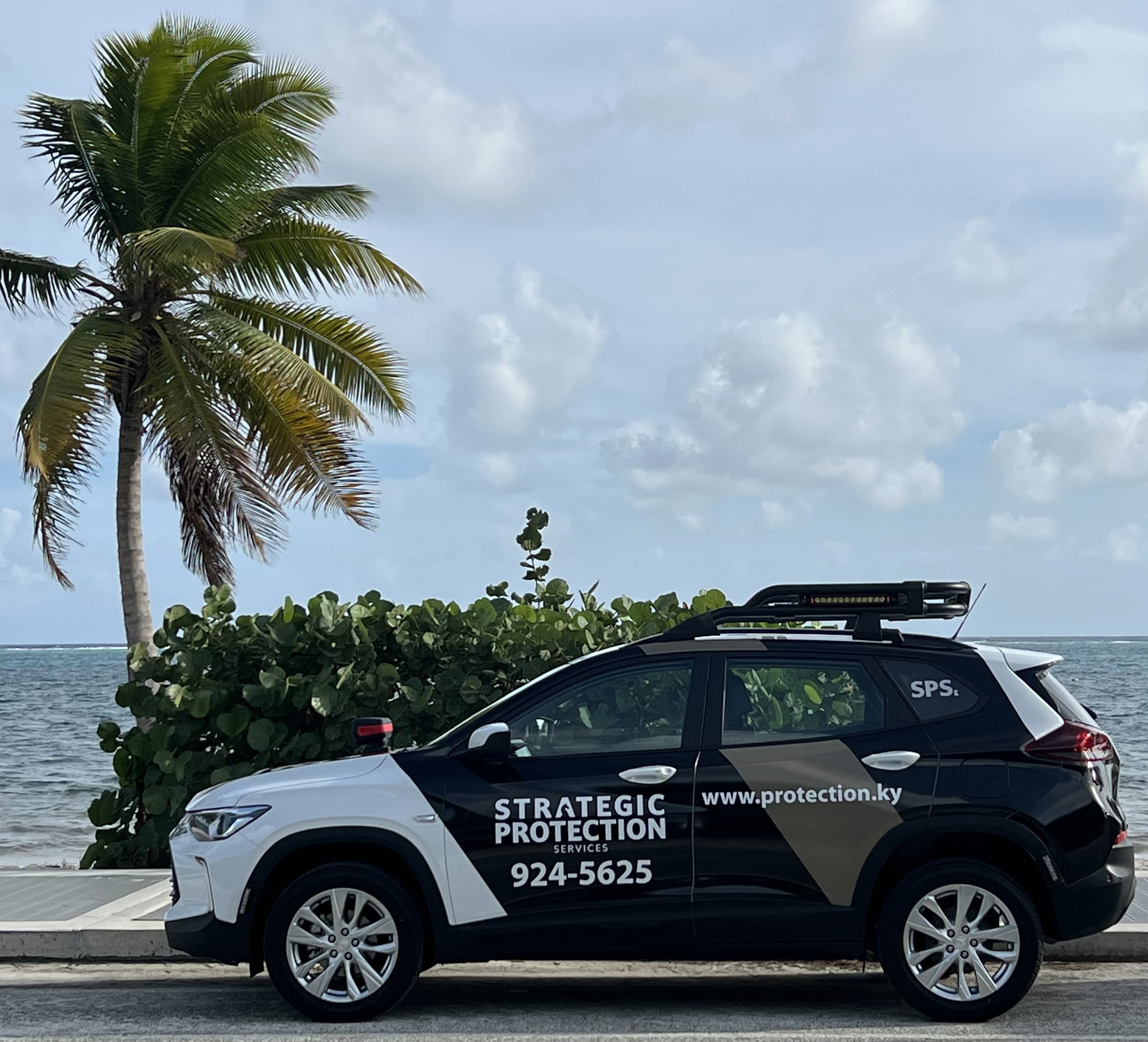 Strategic Protection Services patrol vehicle parked near the ocean in the Cayman Islands, representing reliable security and risk management